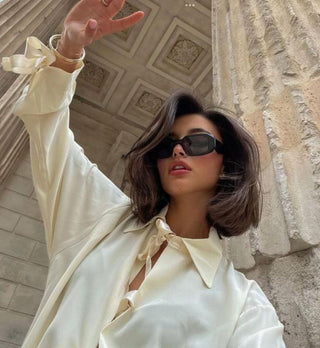 Model with a short, voluminous brunette bob in front of building