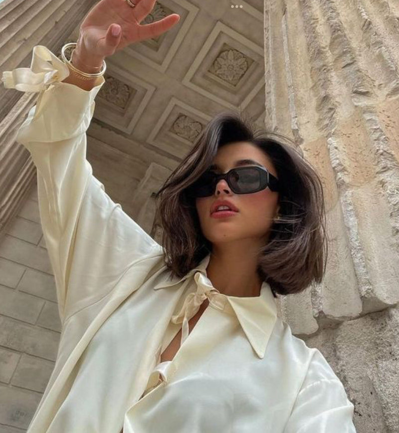 Model with a short, voluminous brunette bob in front of building