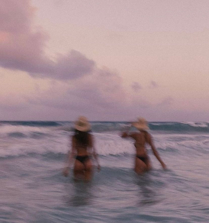 Two women walking into the water, blurry