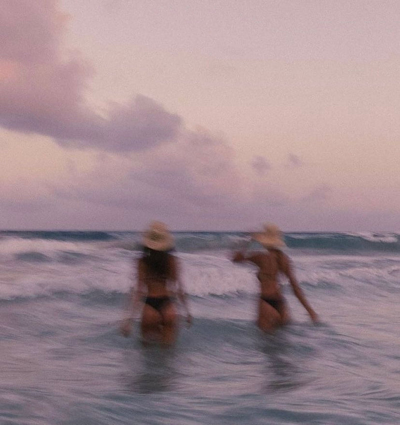 Two women walking into the water, blurry