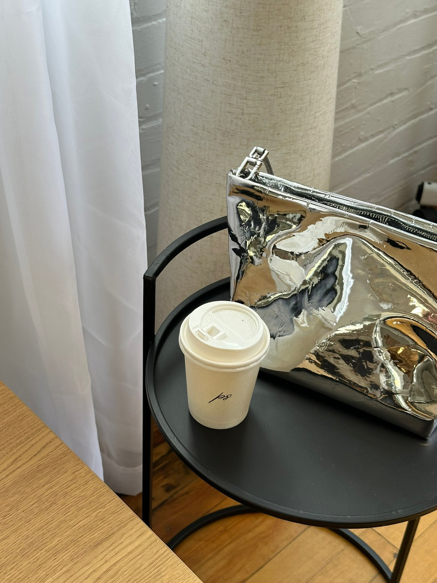 Black side table with coffee cups and a metallic purse at Private Studio in Toronto