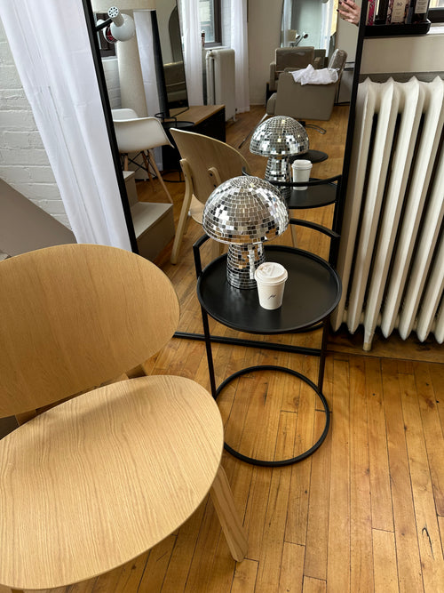 Wooden chair and  black side table with coffee cup and disco ball mushroom at Private Studio in Toronto.