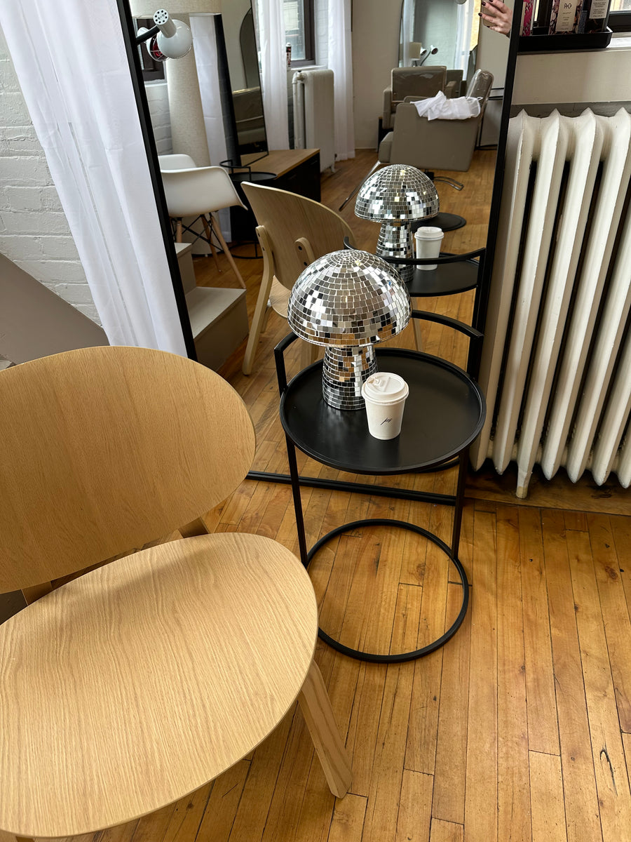 Wooden chair and  black side table with coffee cup and disco ball mushroom at Private Studio in Toronto.